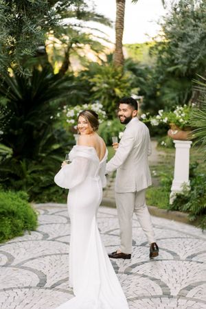 A couple shares a playful moment in a lush tropical garden setting during their wedding.