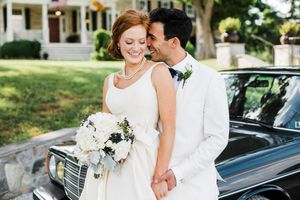 A romantic moment captured beside a vintage car during a summer wedding.