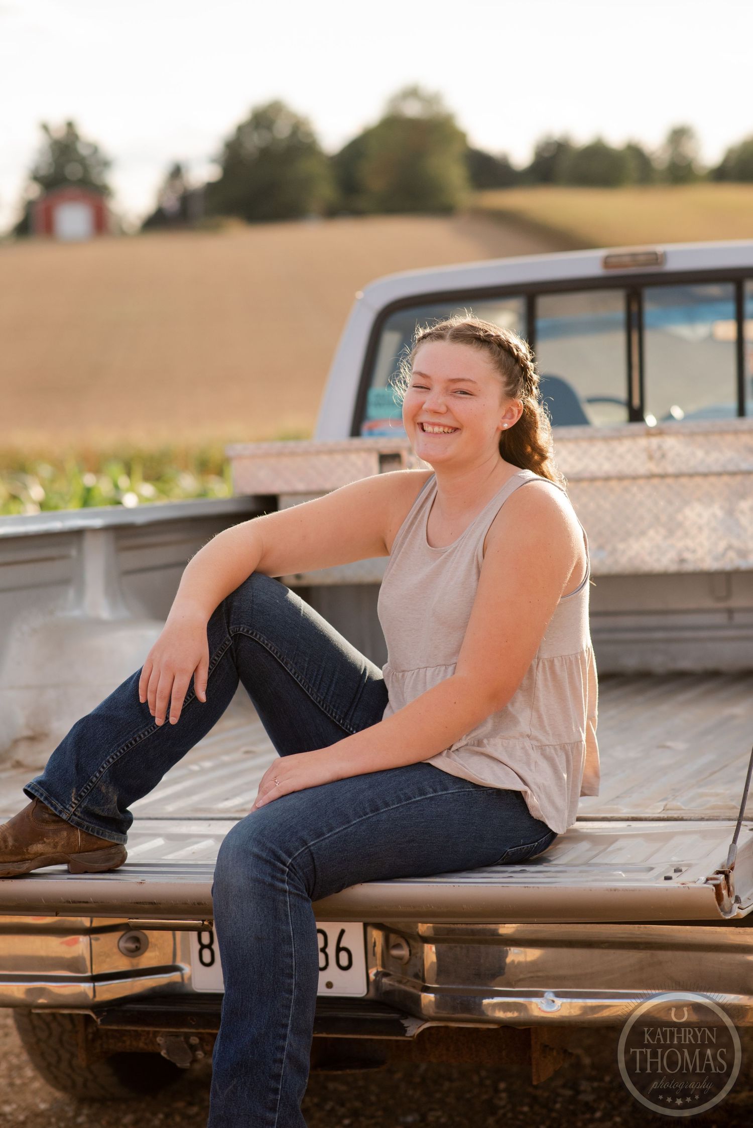 Sunset portrait in pickup truck bed with diamond plate toolbox and rural landscape backdrop.