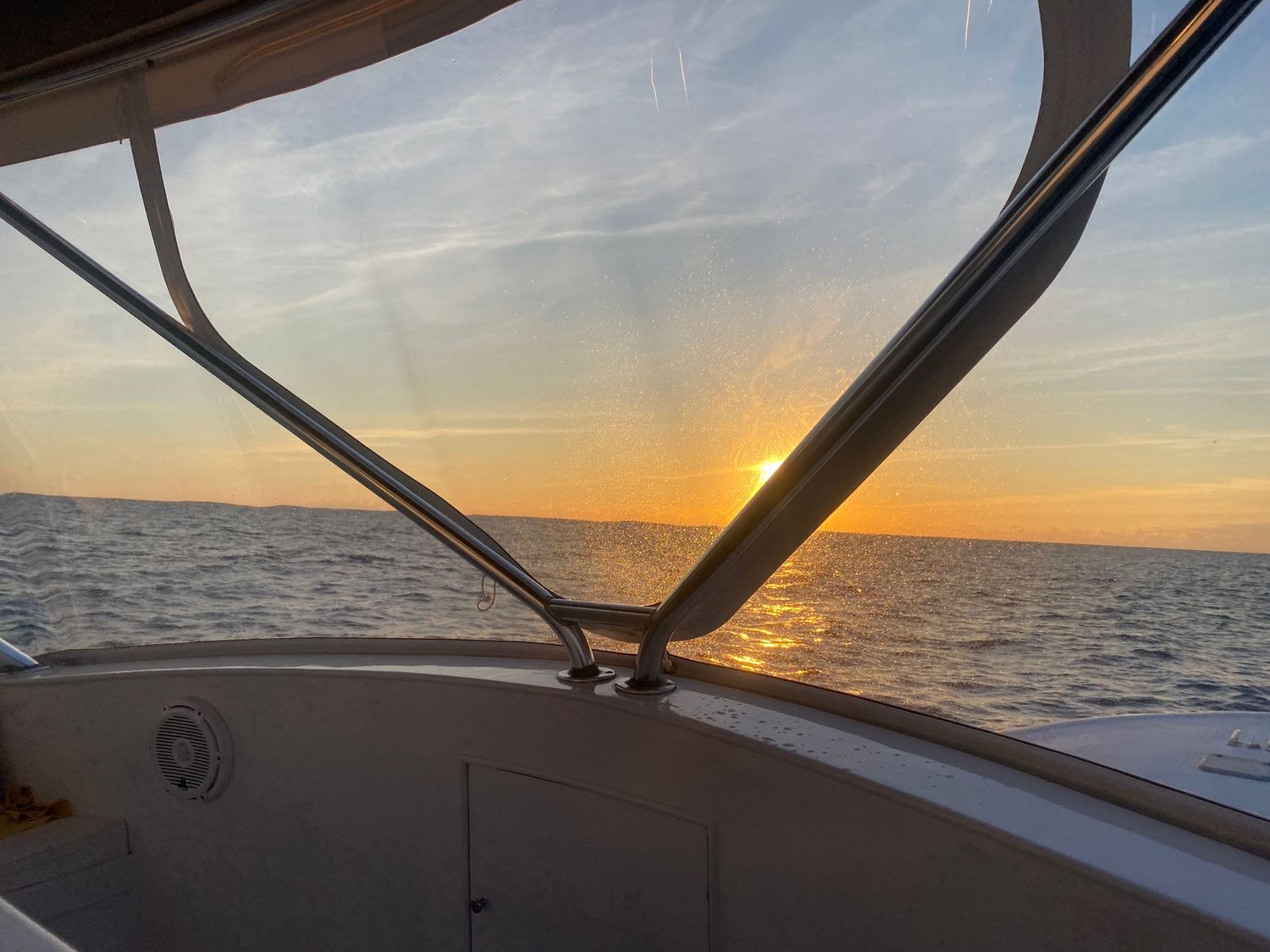 Scenic ocean sunset view through boat windshield while sailing.