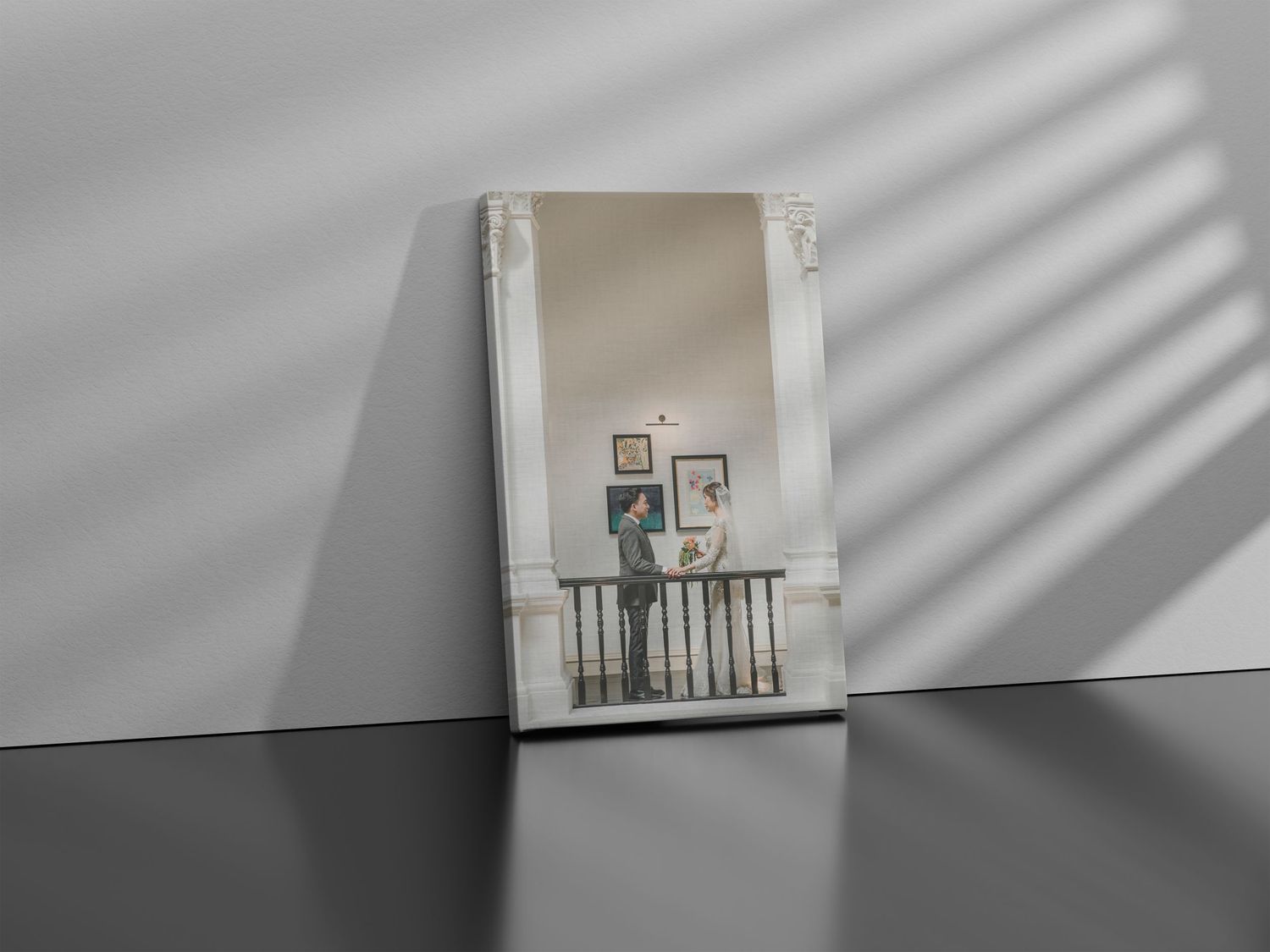 Wedding album presentation with soft shadow patterns on a white wall.