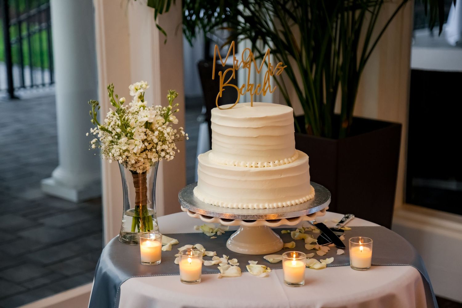 An elegant white tiered wedding cake display with candles and floral arrangements.