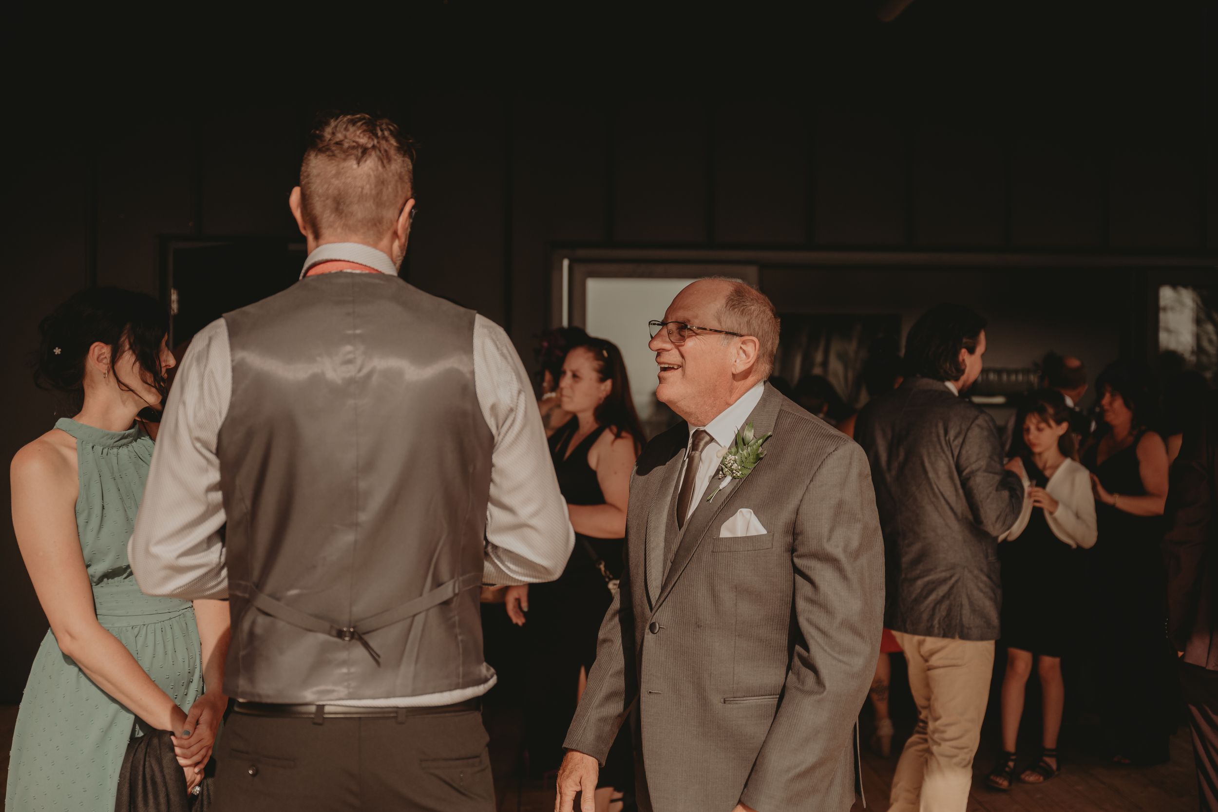 Guests mingle and socialize during a formal event in a dimly lit indoor venue.