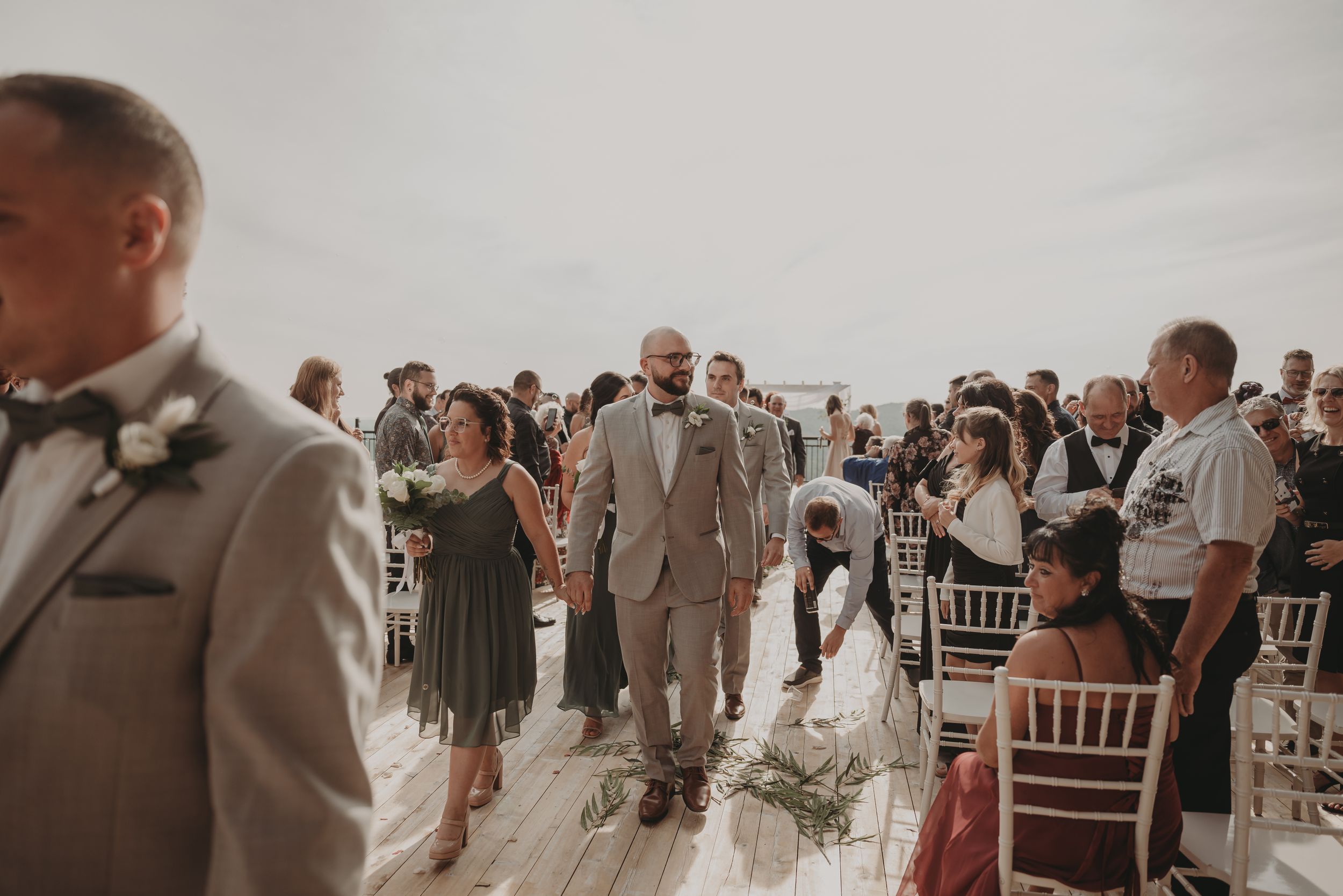 Wedding guests mingle on an outdoor deck during a ceremony with scenic mountain views.