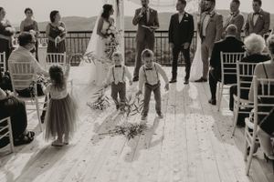 Black and white photo of wedding ceremony participants on outdoor deck with mountain views.