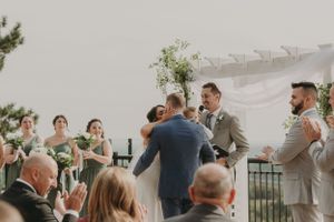 A joyous outdoor wedding ceremony moment with guests and scenic mountain backdrop.
