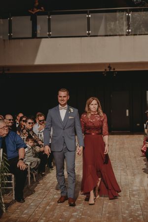 Wedding party members walk down the aisle in formal attire during ceremony processional.