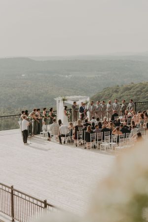 An outdoor mountain wedding ceremony setup with white chairs and scenic valley views.