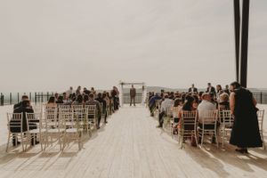 Wedding ceremony setup with white chairs arranged in rows on an outdoor deck.