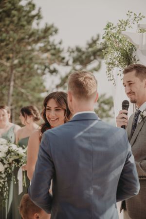 A joyful moment during wedding vows on a terrace with greenery and white decor.