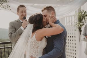 A romantic first kiss moment during an outdoor wedding ceremony with white lattice decor.