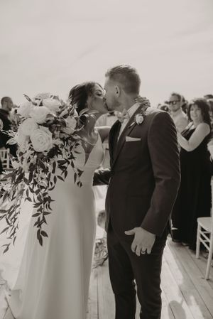 An intimate wedding ceremony moment on a scenic outdoor deck with dramatic florals.