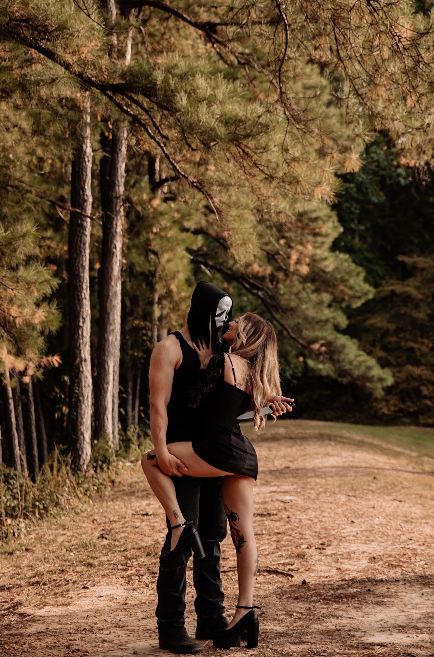 Two people share an intimate moment on a forest trail during golden hour.