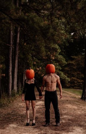 Halloween themed forest photoshoot featuring pumpkin heads and dramatic poses on a dirt path.