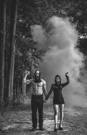 Misty forest scene with masked figures in black and white photography.