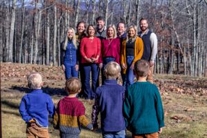 A multi-generational family photo with adults standing and children sitting in front.