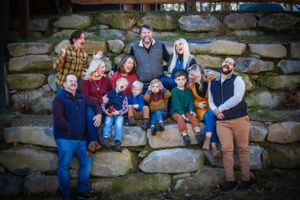 Large group poses together on rustic stone steps during a fall family photo session.