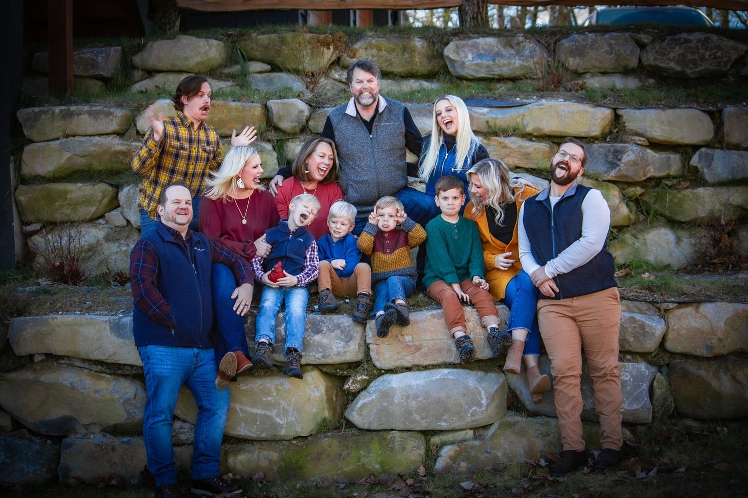 Large group poses together on rustic stone steps during a fall family photo session.