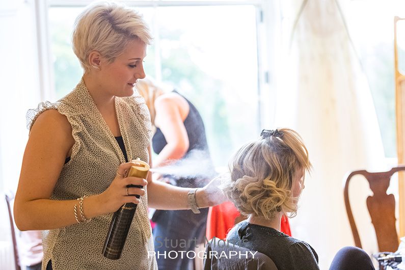the hairdresser gives one of the bridesmaids a blast of hairspray