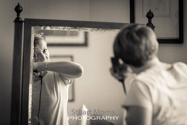 bridesmaid reflected in a mirror straightens her hair during the bridal prep