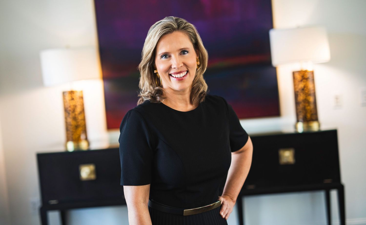 Professional portrait in modern office setting with decorative lamps in background.