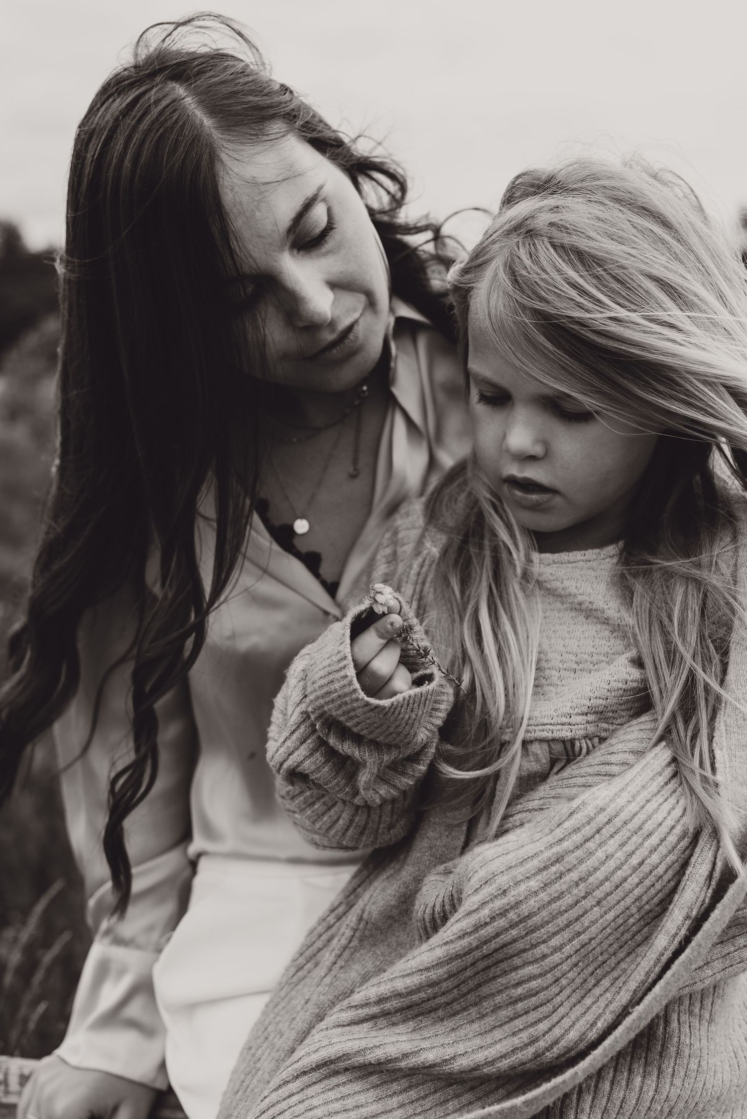 Tender black and white portrait of mother and child sharing an intimate moment outdoors.