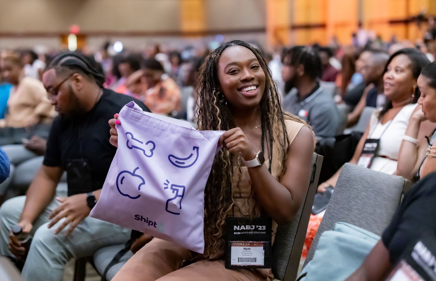 Conference attendee showing excitement while holding up branded merchandise at an event.