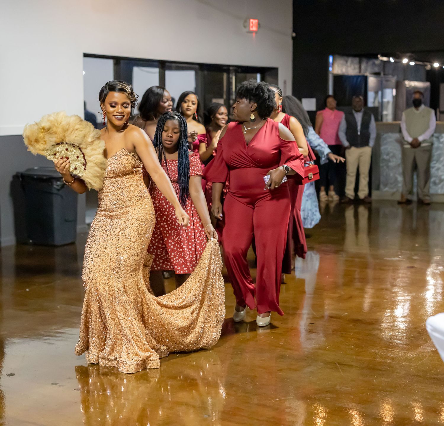 A group of elegantly dressed people walking through an indoor venue during a celebration.