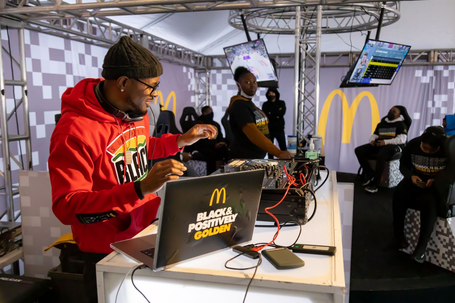 Gaming setup with McDonald's branding and people using laptops at an esports event.