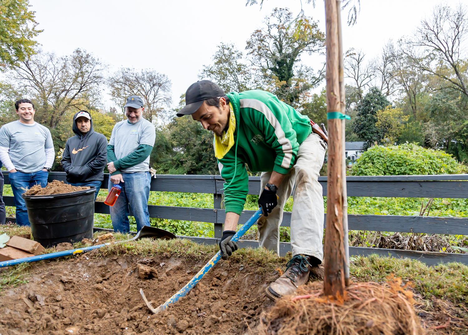 Group of volunteers planting trees and doing community service work in a garden.