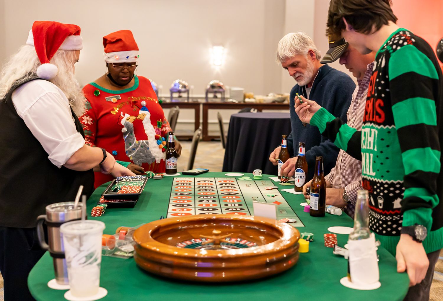 People in festive holiday attire playing roulette at a casino table.