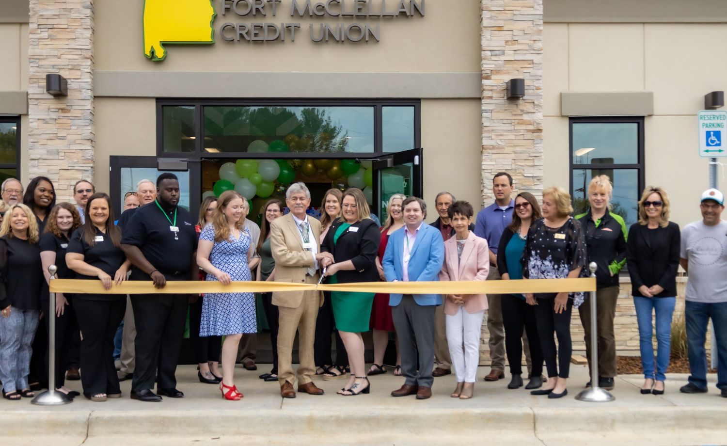 Large group gathered for ribbon cutting ceremony outside new business storefront.