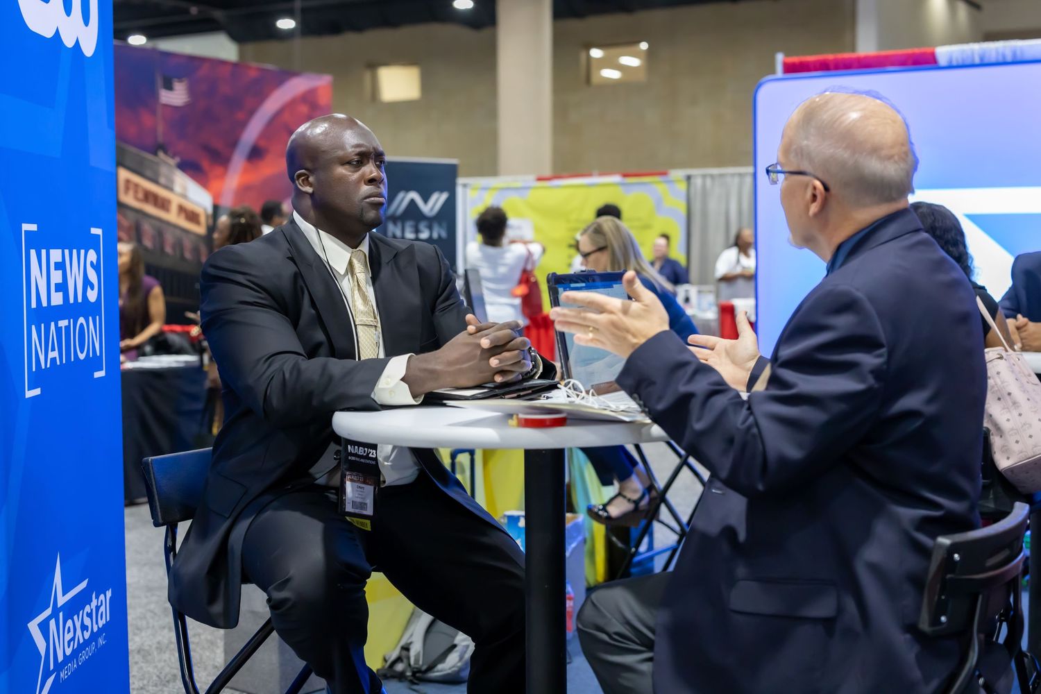 Professional networking interaction at a career fair booth with CNN branding.