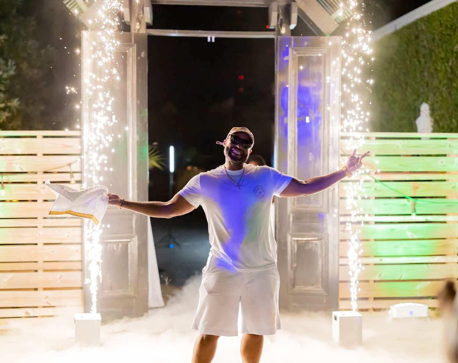 Outdoor nighttime celebration with sparklers creating streams of light against dark sky.