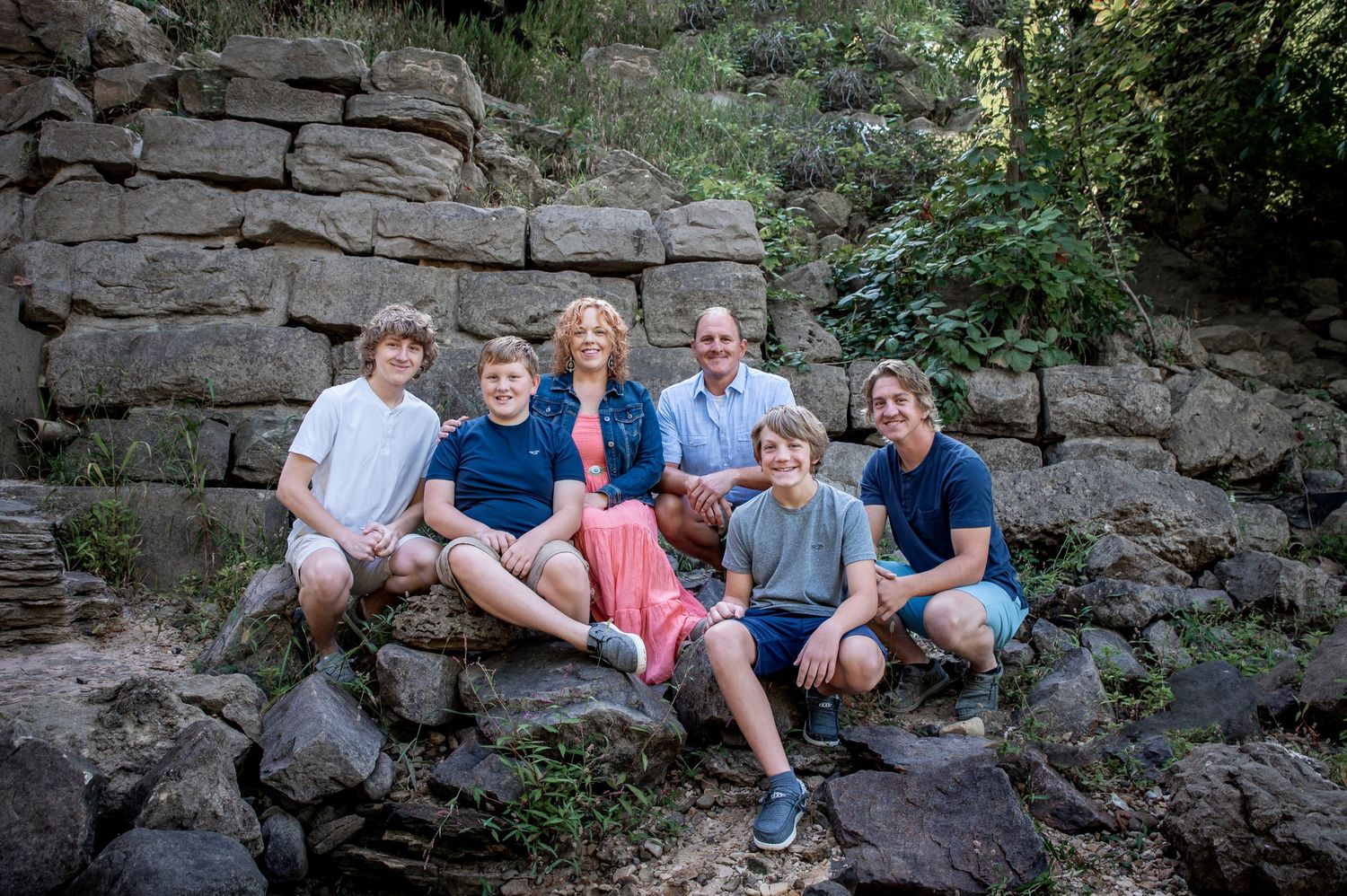 A group sits together on stacked stone steps in a natural outdoor setting.
