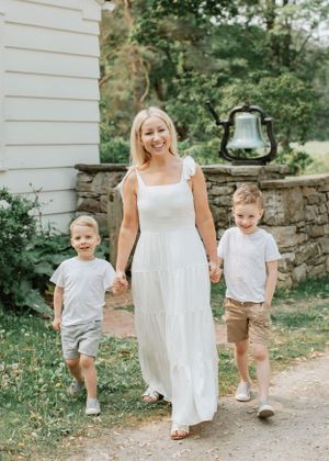 Family walking together outdoors in coordinated summer outfits with a white dress and casual attire.