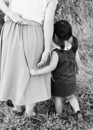 Black and white image capturing a tender moment of holding hands while walking outdoors.