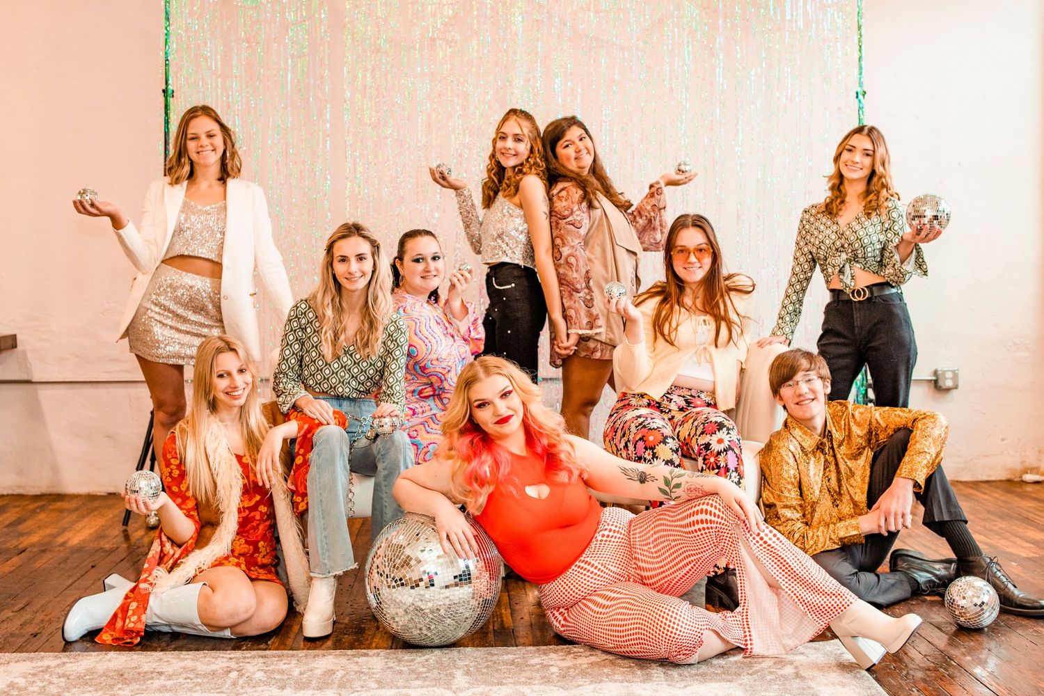 Group of women posing together at a glittery party celebration with disco balls and festive decorations.