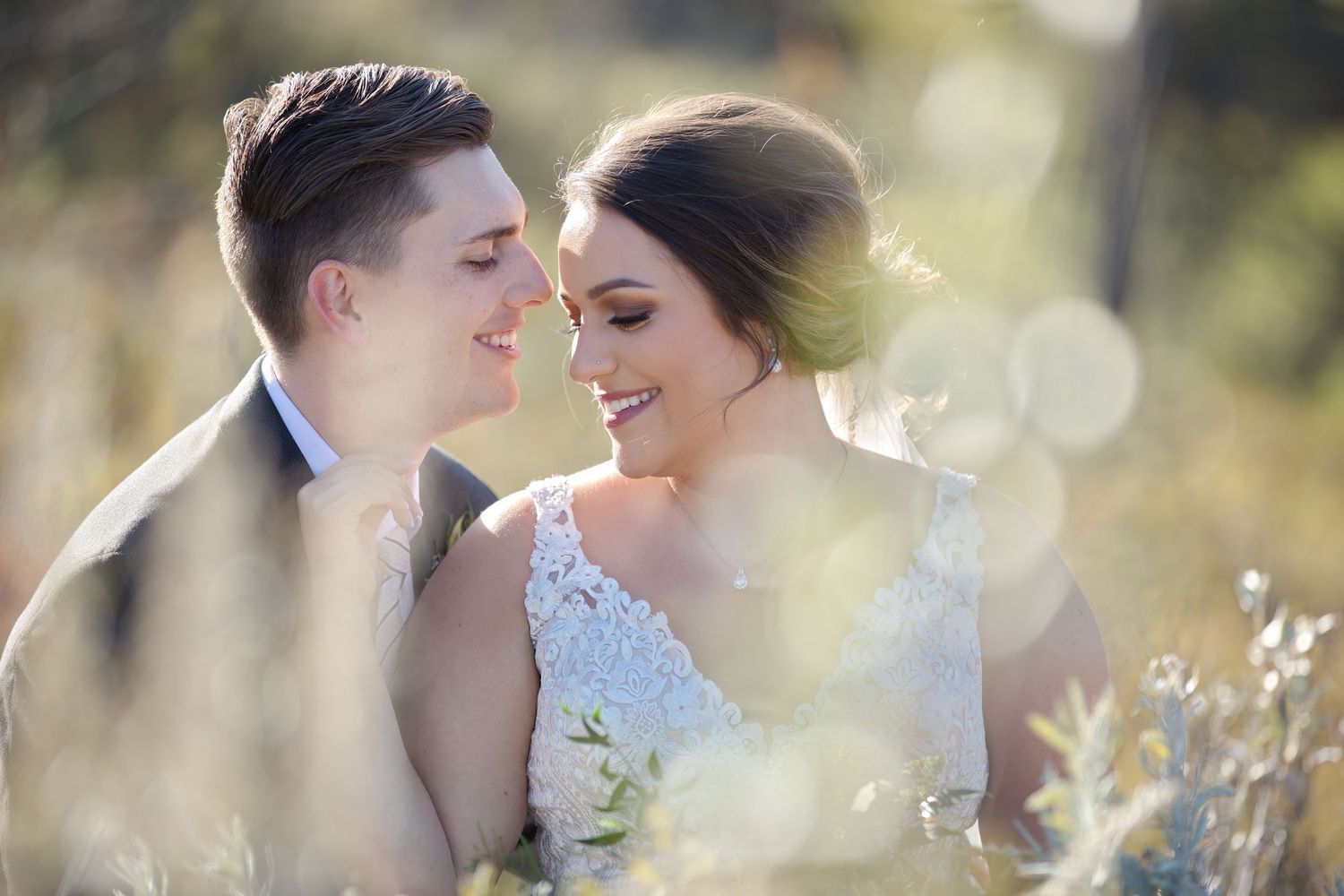A romantic wedding portrait of a couple embracing in a sun-drenched meadow.