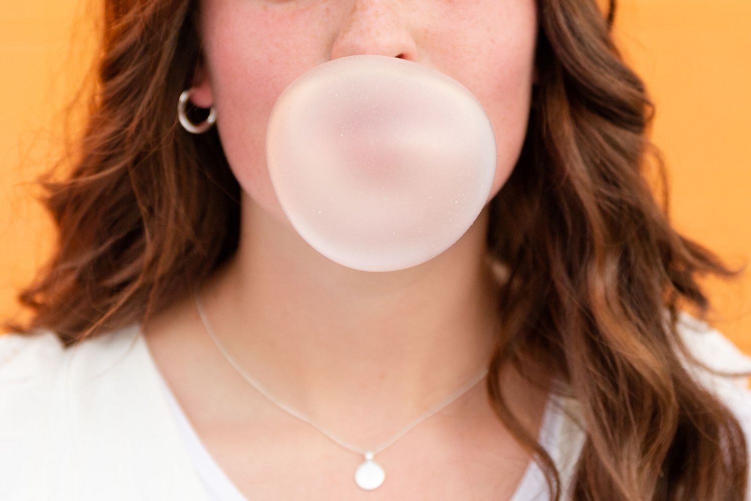 a woman blowing a bubble with the focus on the bubble