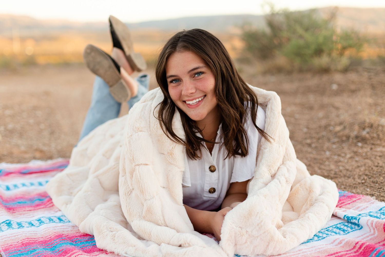 woman laying on stomach wrapped in a blanket smiling at camera