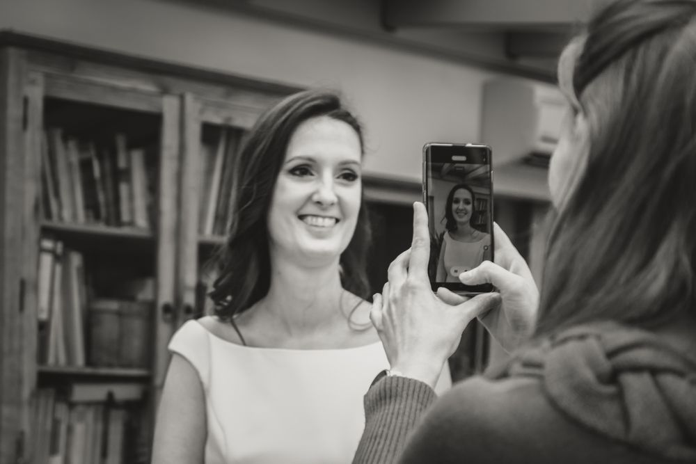 Someone taking a photo with a mobile phone in a room with bookshelves.