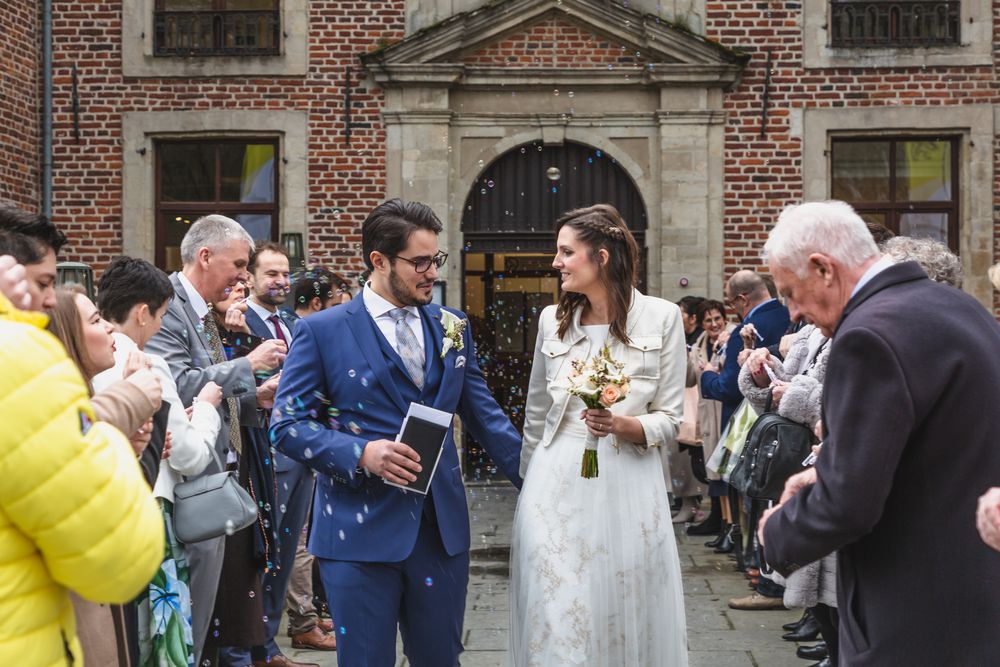A wedding celebration outside a traditional brick building with guests cheering.