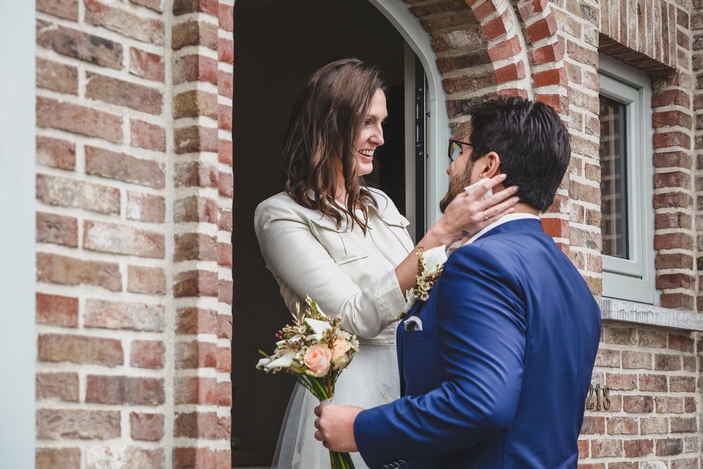 A couple shares an intimate moment outside a brick building entrance.