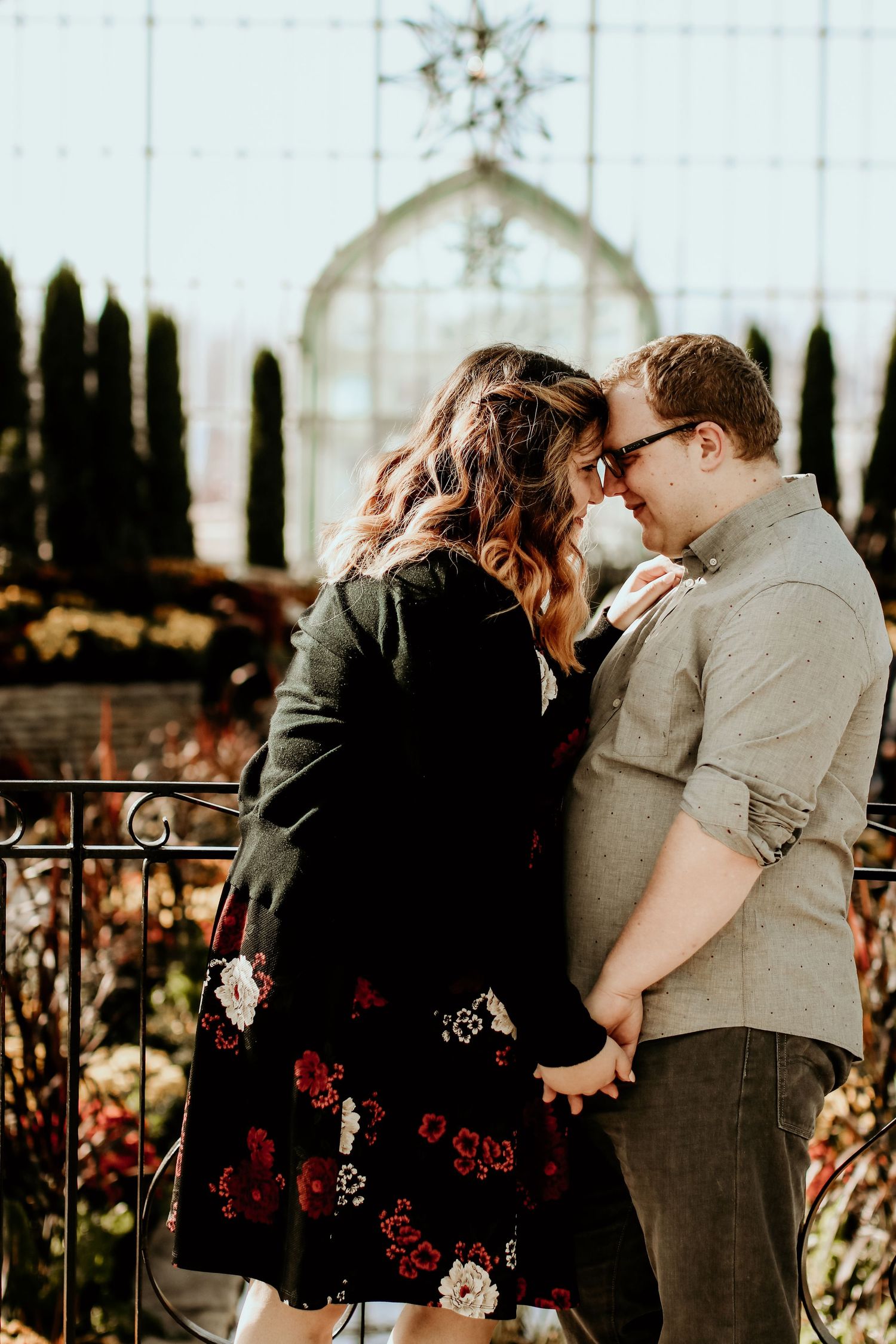 Romantic couple sharing an intimate moment in front of an ornate garden gate.