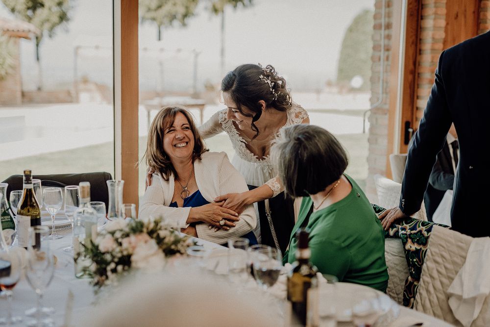 Bride shares a joyful moment with female wedding guests at a beautifully decorated reception table.