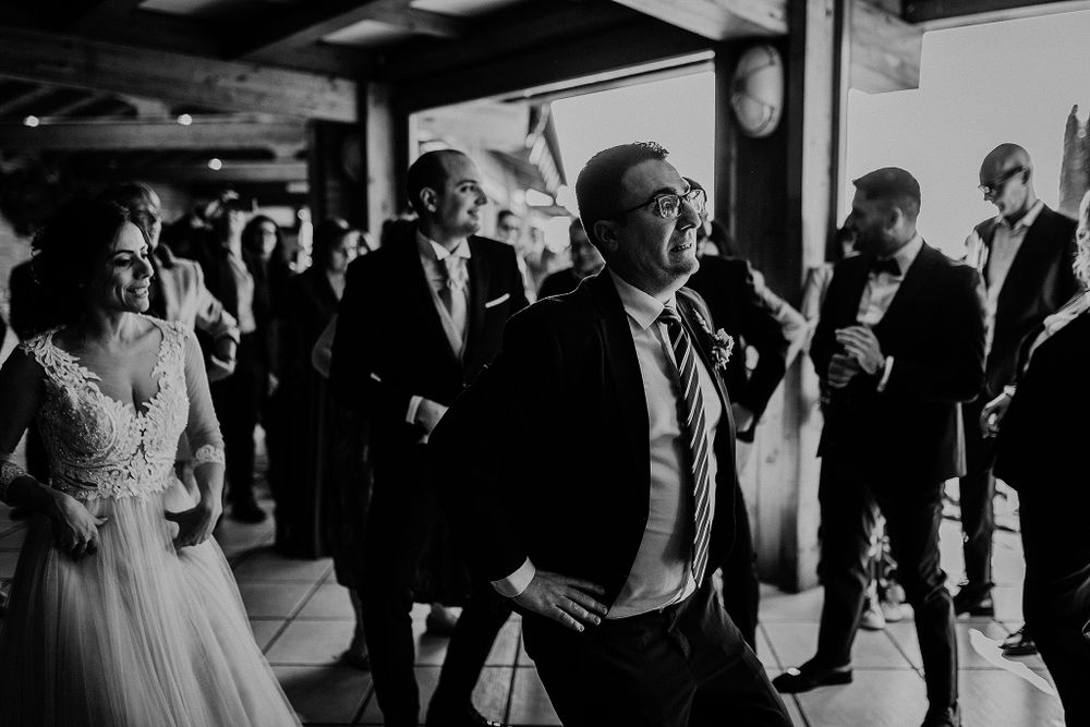 Wedding guests dance and celebrate in black and white photo at a lively outdoor wedding reception.