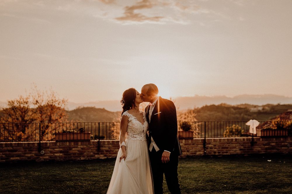 Bride and groom sharing a kiss at sunset with scenic countryside views behind them.