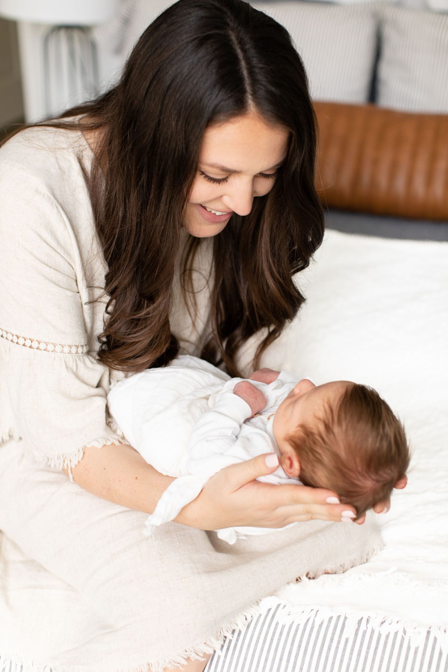 Parent and baby share loving moment on couch with leather backrest in background.