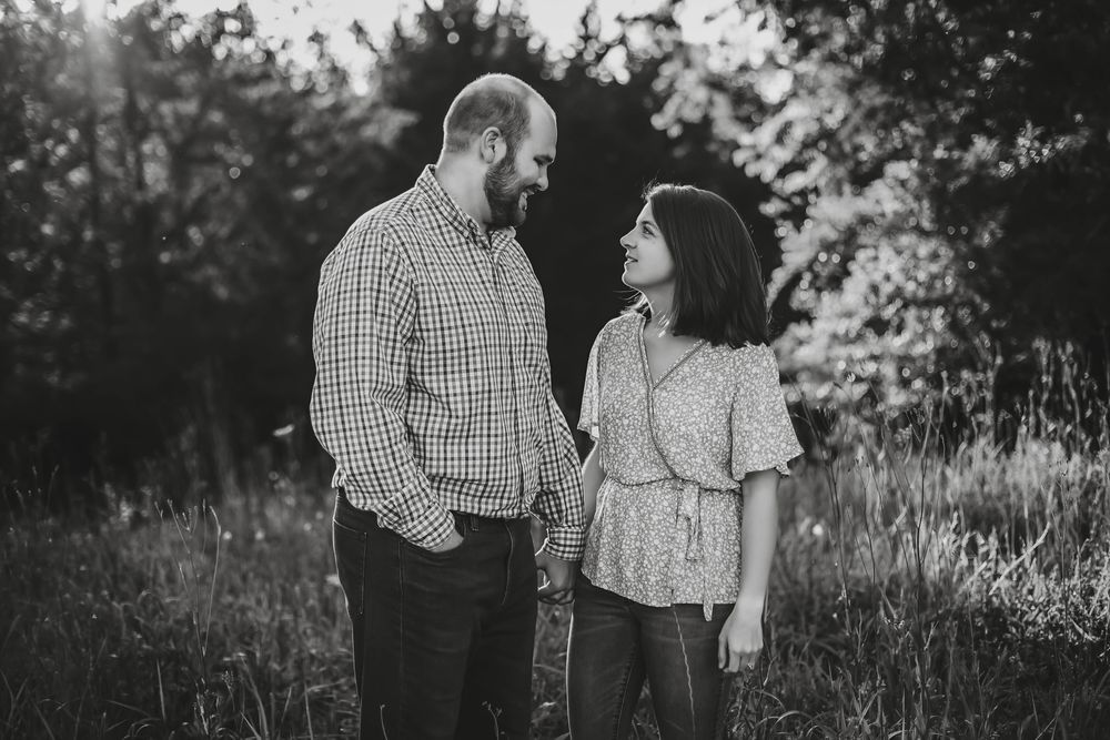 A couple shares an intimate moment outdoors in black and white photography.